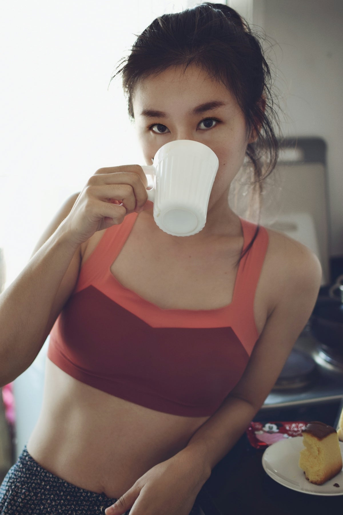 woman in red sports bra drinking from white ceramic mug