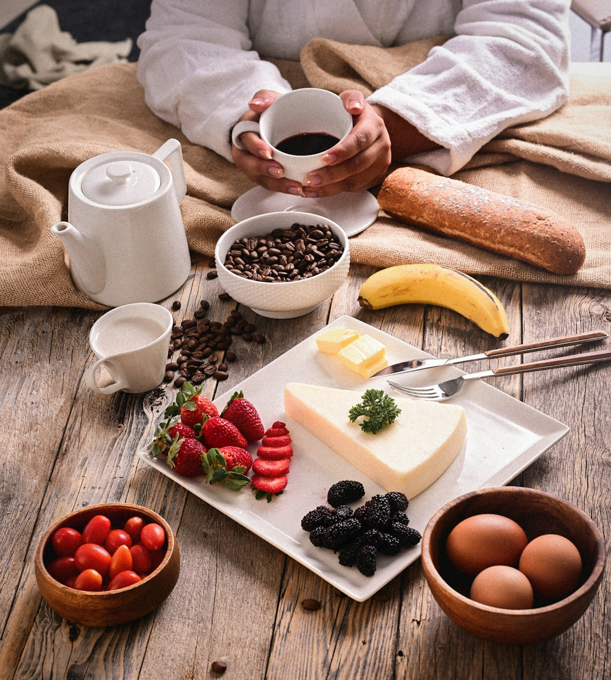 a person holding a cup of coffee over a plate of food