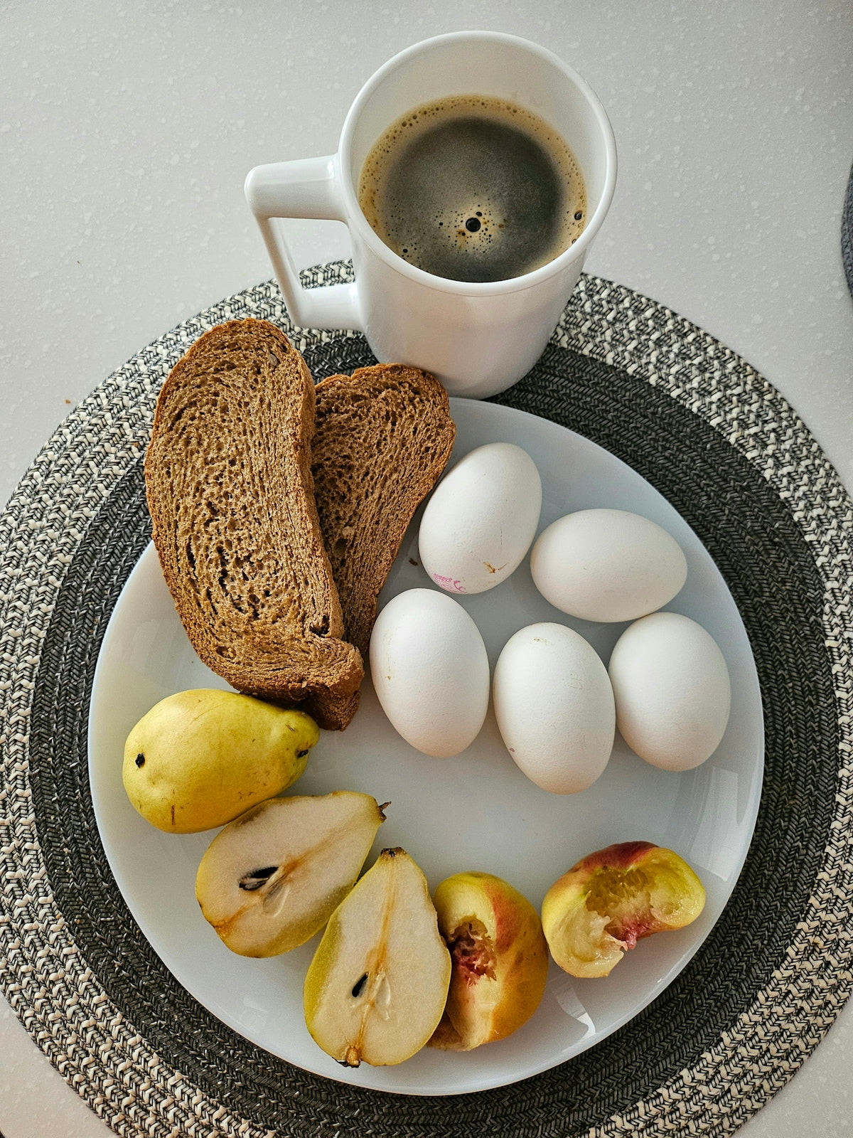 A white plate topped with sliced apples and a cup of coffee