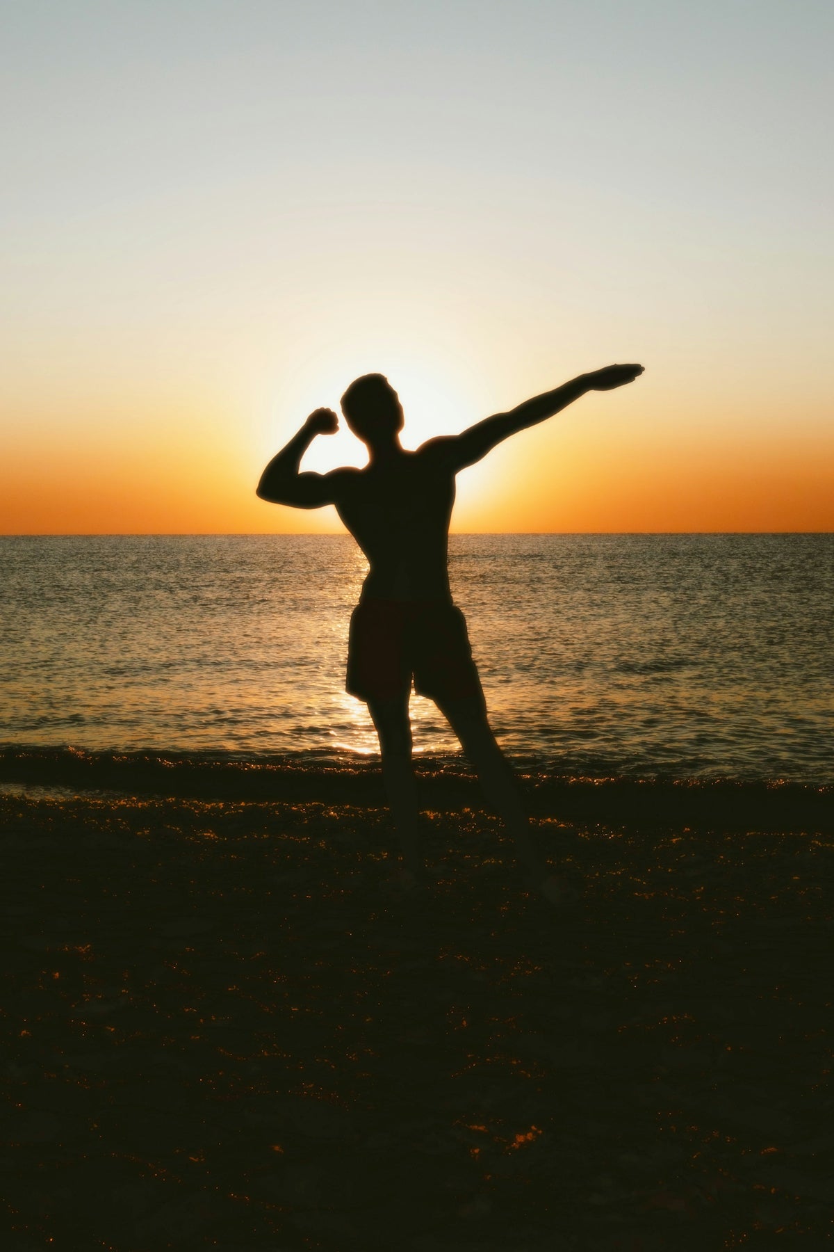 A man standing on top of a beach next to the ocean