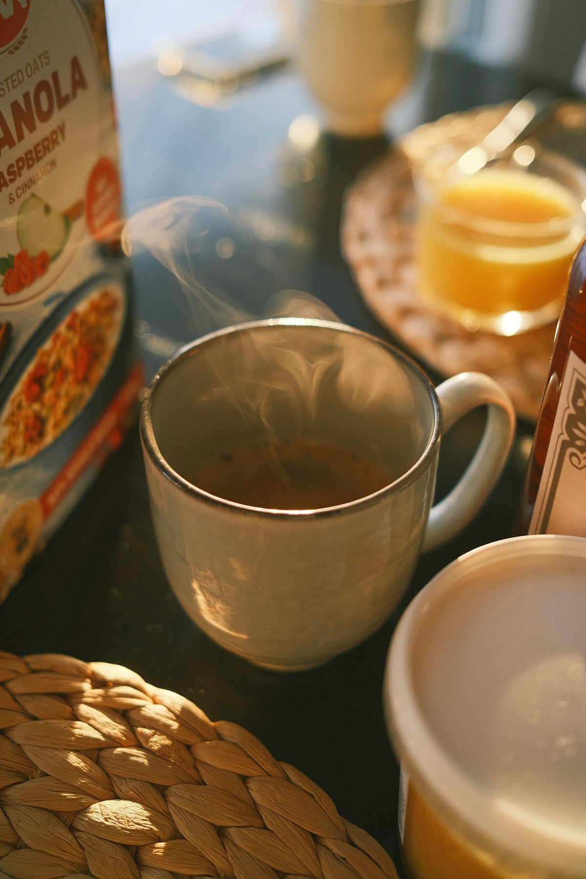 A table topped with a cup of coffee next to a box of granola